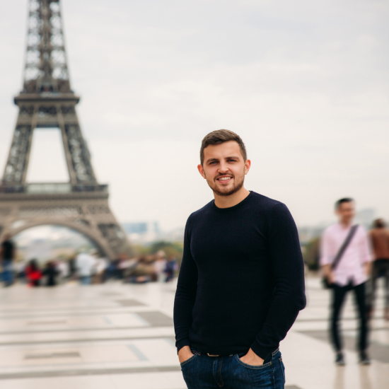 A student seating under a lampost with the Eifeel Tower in the background